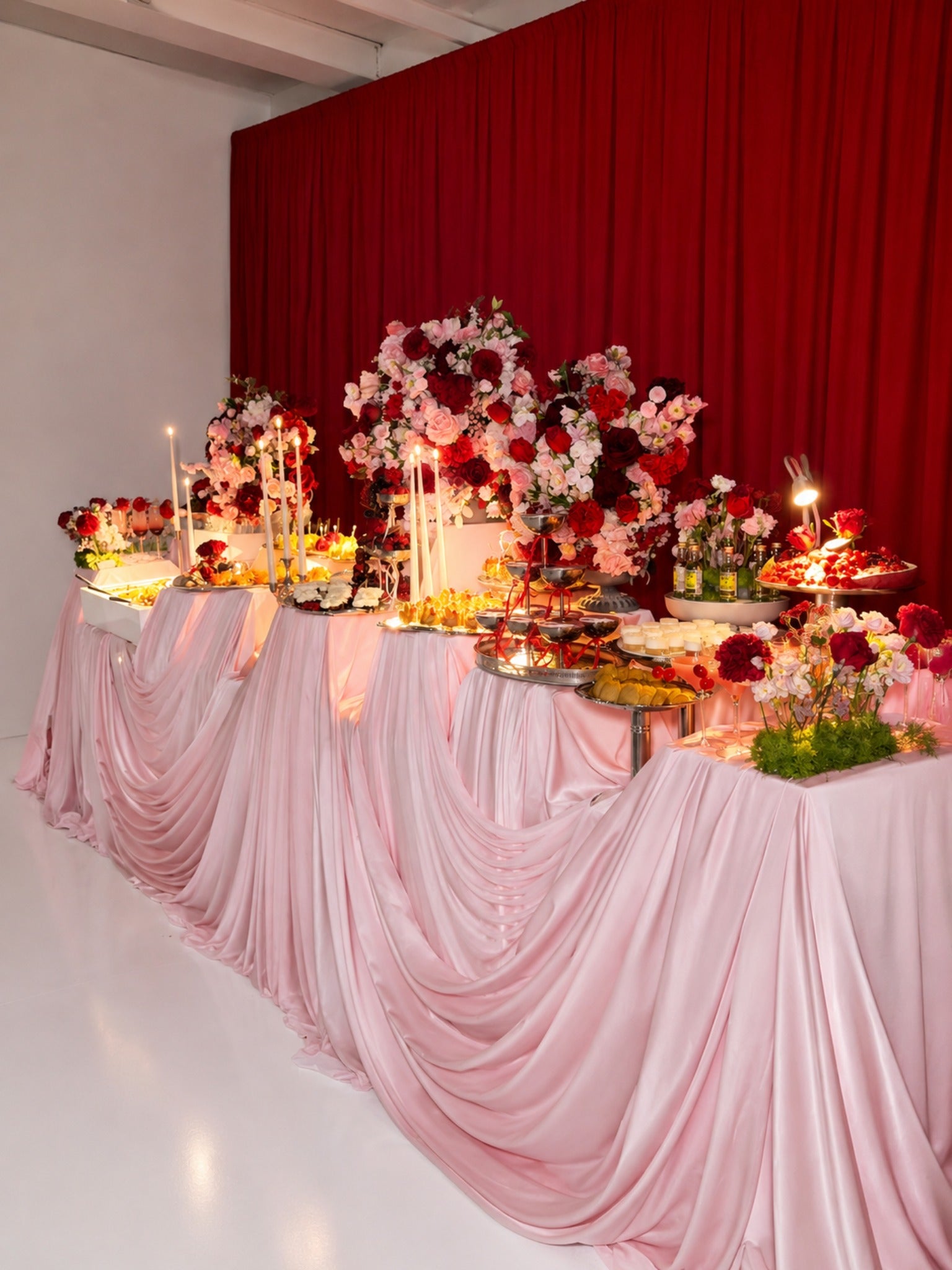 Styled event setup with draped pink linens and floral accents